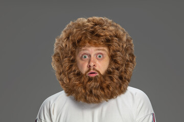 Half-length portrait of young very hairy man isolated over grey background.