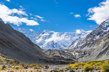 Fototapeta na wymiar Beautiful panorama of high rocky mountains with mighty glaciers and snowy peaks against the blue sky and clouds