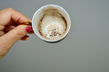 close-up - a coffee cup on a gray background in the hand of a fortune-teller who is guessing on the...