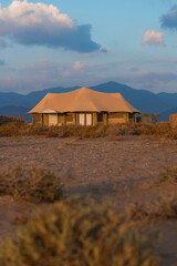 Beige tent  with beautiful sunrise and mountains on the background.  Eco retreat in the mountains. 