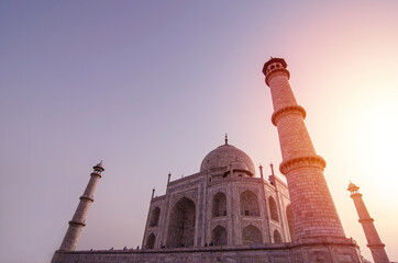 Fototapeta premium Taj Mahal on a bright clear day and sunset. Mosque for lover in city of Agra, Uttar Pradesh, INDIA. The most famous landmarkof of INDIA. Taj Mahal lovely marble white building. Layout for magazine.