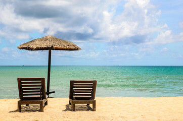 The beach chairs on sandy beach with cloudy blue sky and sun in the summer