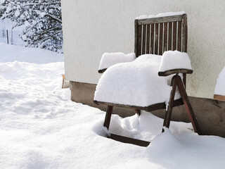 Mit viel Schnee bedeckter Holzstuhl im Winter