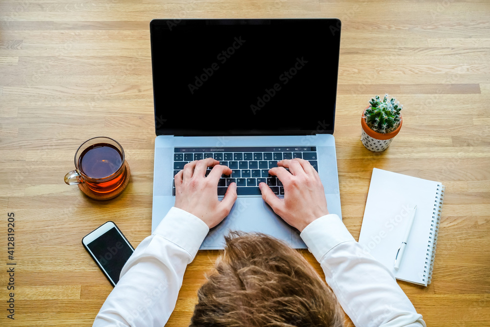 Canvas Prints a male programmer works in front of a laptop screen in a bright office or remotely from home. workpl