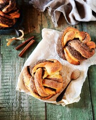 Braided buns with cinnamon on a wooden background, rustic style