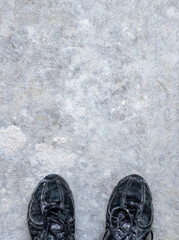 Black dirty and dusty sneakers or sport shoes standing on the dusty white cement floor