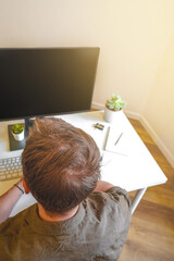 A male programmer works in front of a laptop screen in a bright office or remotely from home. Workplace
