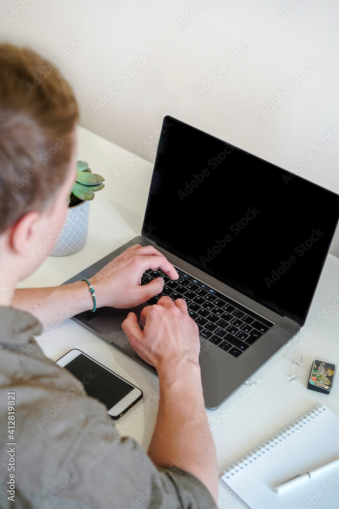 Sticker a male programmer works in front of a laptop screen in a bright office or remotely from home. workpl