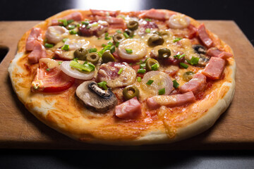 Just baked pizza. Pizza on wooden board close up. Pizza with mushrooms and olives.