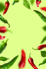 Frame of Flying green and red chili pepper, leaves on green background. Seasoning for dish, fresh hot pepper, spicy spices for cooking, cayenne pepper, food. Creative concept of food, vegetables