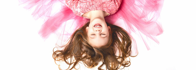 little Princess. Portrait of a cute Caucasian little girl in an evening bright pink dress lies on a...