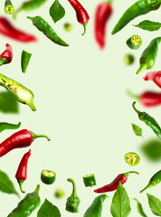 Frame of Flying green and red chili pepper, leaves on green background. Seasoning for dish, fresh hot pepper, spicy spices for cooking, cayenne pepper, food. Creative concept of food, vegetables