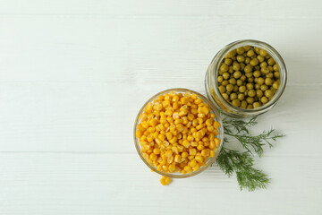 Canned peas and corn on white wooden background