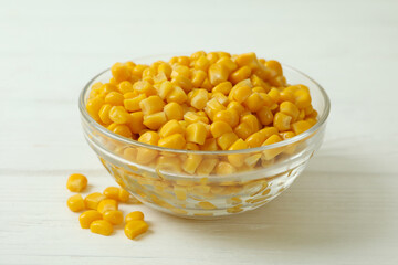 Bowl with canned corn on white wooden background