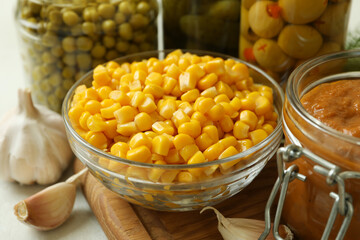 Wooden board with canned food on white textured table