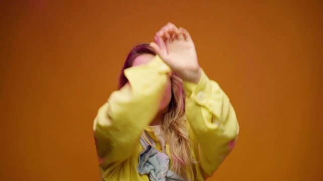 Trendy young woman dacing against yellow background