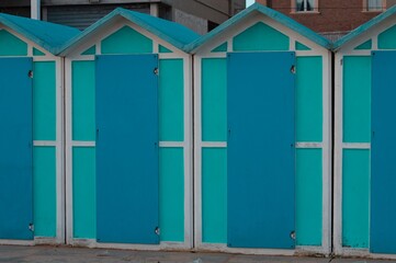 A series of turquoise beach sheds with blue wooden doors in a winter day (Pesaro, Italy, Europe)
