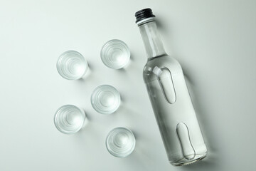Bottle and shots of vodka on white background