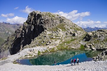 An isolated turquoise lake in the Italian Alps with people hiking and climbing the mountain...
