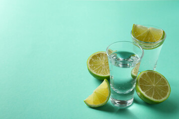 Shots and lime slices on mint background, space for text
