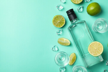 Bottle and shots of vodka, limes and ice on mint background, top view - obrazy, fototapety, plakaty