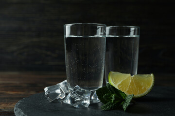 Tray with shots of vodka on wooden background