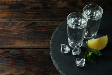 Tray with shots of vodka on wooden background