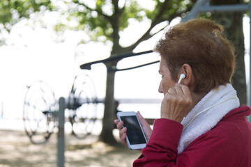 senior woman listening to music with headphones while doing sports or exercises