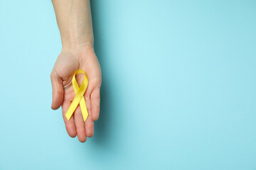 Female hand hold child cancer awareness ribbon on blue background