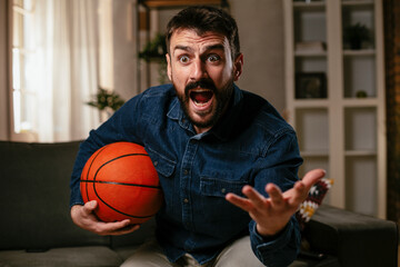 Happy man enjoying at home. Man watching sports game on tv...