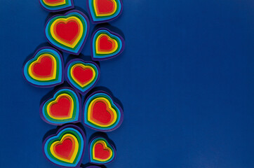 Valentine day background with rainbow hearts on dark blue paper as border, copy space, top view.