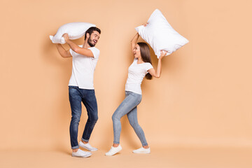 Full body profile side photo of young couple play pillow battle fight happy positive smile excited...