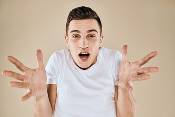 Cute emotional man white t-shirt gesture with hands cropped view beige studio background