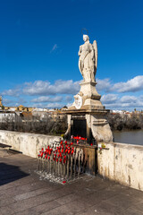 Fototapeta premium statue with candles and offerings on the Roman Bridge in Cordoba