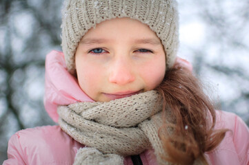 Sad child girl in warm knitted winter clothes spent time outdoors and got frozen.