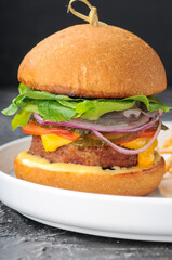 large burger in a white plate upright
