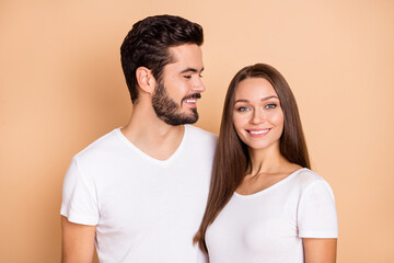 Photo of cute adorable married couple dressed white t-shirts smiling embracing isolated beige color background