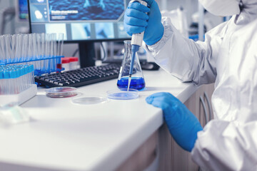 Medicine scientist pouring liquid on petri dish working in lab with micropipette. Chemist in modern...