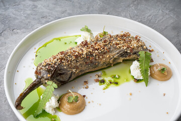 eggplant with nuts and pistachio sauce on a white flat plate
