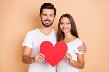 Portrait of handsome guy pretty lady hug hands hold red paper heart card isolated on beige color background