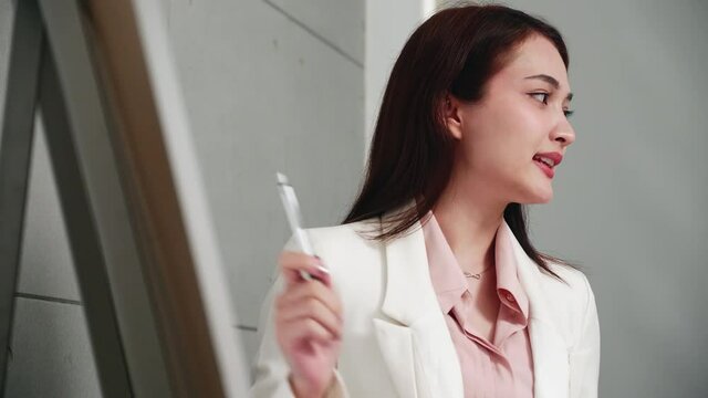Businesswoman holds meeting presentation conference speaker and presentation explain project strategy on whiteboard at office boardroom.