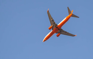 red passenger plane close-up flying in the sky