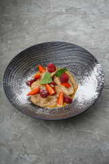 lined dumplings with berries and honey in a beautiful gray plate vertically

