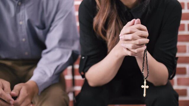A young Christian couple sitting in a church praying to God.