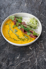 meat slices with mashed peas on a white plate on a dark background vertically
