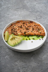 salmon tartare with avacado in a white plate on a gray background top view vertical
