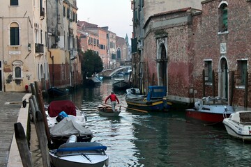 Fototapeta na wymiar View of a canal with a man rowing in an authentic and residential Venice 