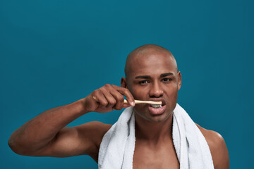 Angry man brushing teeth with bamboo toothbrush