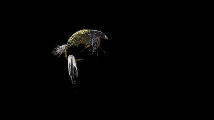 Handmade fishing fly close-up on a dark background.