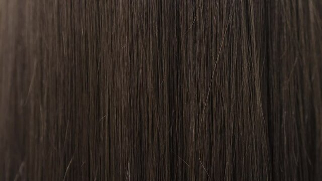 Demonstration of smooth and silky hair after straightening it with a steampod. High quality 4k footage. Close-up of beautiful smooth and silky brunette hair.